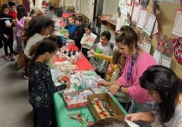  Crissman second grade students stand behind table with treats while students look at options to buy